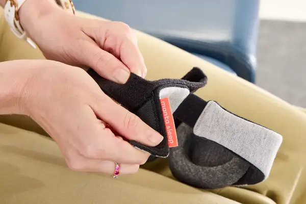 A person adjusting the velcro strap on the Manta Sleep Mask