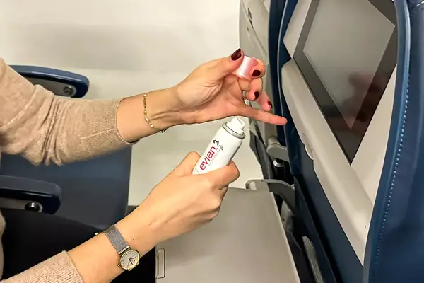 A person removing the lid of the Evian Facial Spray