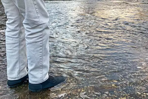 A person stands in water while wearing the Bogs Arcata Urban Leather Mid Men