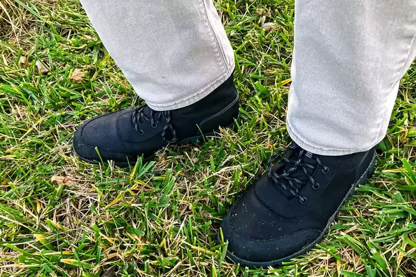 A person stands in grass while wearing the Bogs Arcata Urban Leather Mid Men