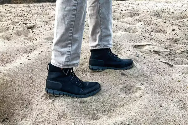 A person walks through sand while wearing the Bogs Arcata Urban Leather Mid Men