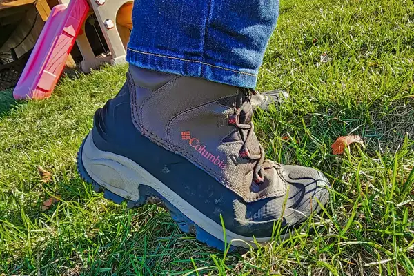 A side view of a person wearing the Columbia Men’s Bugaboot III Boot in grass
