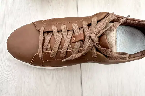 A Kizik Women’s Vegas Sneaker on a wooden floor