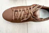 A Kizik Women’s Vegas Sneaker on a wooden floor