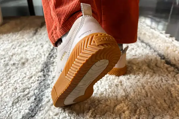 A Sorel Ona Ave Low Waterproof Sneaker posed to show the bottom on a rug