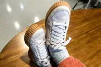 A close-up of the Sorel Ona Ave Low Waterproof Sneakers worn on a wooden surface