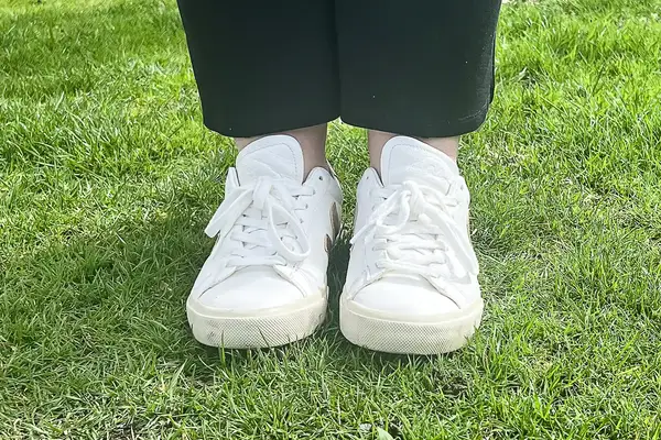 A woman wears Veja Campo Low Top Sneakers in the grass