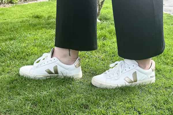 A woman wears Veja Campo Low Top Sneakers in the grass