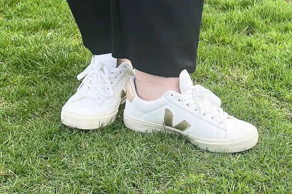 A woman wears Veja Campo Low Top Sneakers in the grass