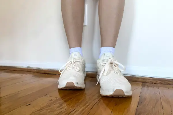 A close-up of the Adidas Ultraboost 1.0 sneakers worn on a wooden floor