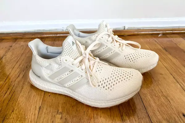 The side-view of the Adidas Ultraboost 1.0 shoes worn on a wooden floor