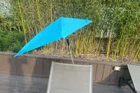 The Sport-Brella Versa-Brella Umbrella attached to the back of a lawn chair on a patio