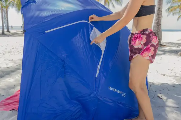 Person unzipping the outer window of the Sport-brella Premiere UPF 50+ Umbrella on the beach