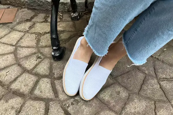 A Kizik Women’s Vegas Sneaker on a wooden floor