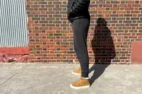 A person standing sideways by a brick wall while wearing the Quince Mongolian Cashmere Jogger