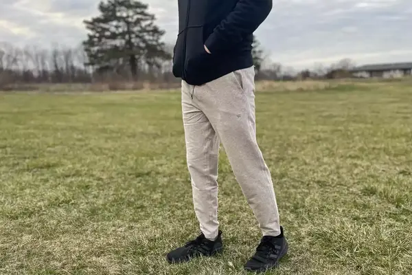A person walks through grass while wearing the Mack Weldon Ace Sweatpant