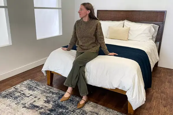 A person sitting on a bed wearing the Finisterre Farne Women