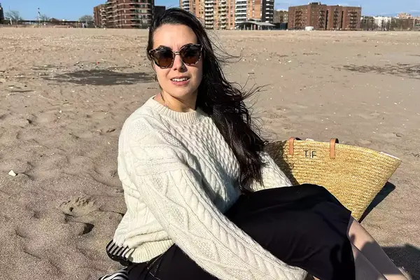 A person sitting on the beach wearing the Buck Mason Cable Crew