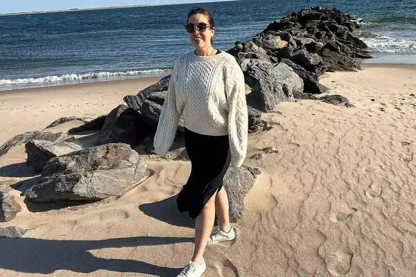 A person standing on the beach wearing the Buck Mason Cable Crew