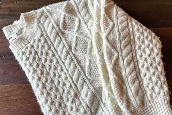 Buck Mason Cable Crew laying on a hardwood floor