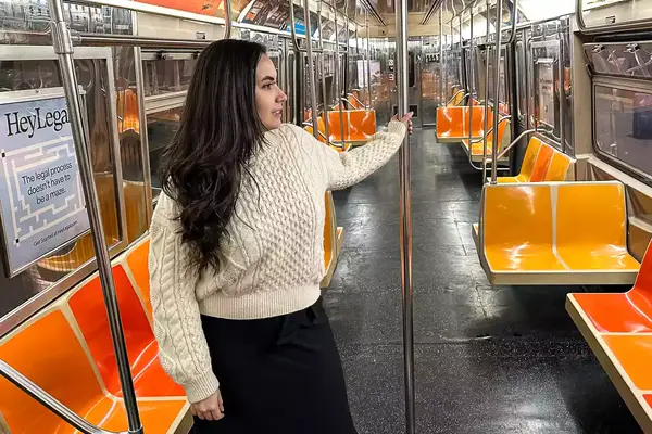 A person standing on a subway wearing the Buck Mason Cable Crew
