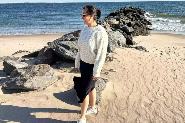 A person standing on the beach wearing the Buck Mason Cable Crew