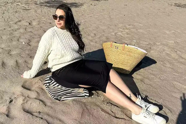 A person sitting on sand wearing the Buck Mason Cable Crew