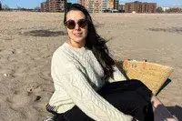 A person sitting on the beach wearing the Buck Mason Cable Crew