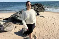 A person standing on a beach wearing the Buck Mason Cable Crew