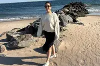 A person standing on the beach wearing the Buck Mason Cable Crew