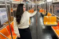A person standing on a subway wearing the Buck Mason Cable Crew