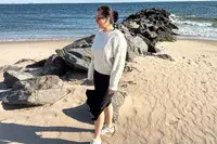 A person standing on the beach wearing the Buck Mason Cable Crew