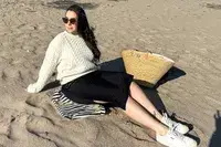 A person sitting on sand wearing the Buck Mason Cable Crew