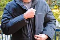 A person unzips the pocket of the Cotopaxi Calidez Men