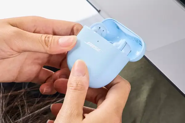 Two hands holding an opened Bose QuietComfort Ultra Earbuds case