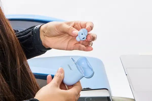 A hand removing a Bose QuietComfort Ultra Earbud from the carrying case