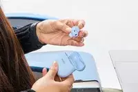 A hand removing a Bose QuietComfort Ultra Earbud from the carrying case