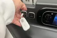 A hand plugging the Twelve South AirFly SE into a headphone port on an airplane