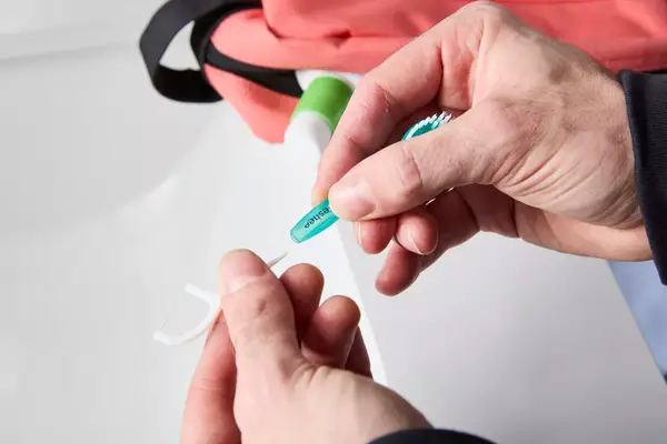 A person attaching the floss tip to the Freshee 5-in-1 Disposable Mini Toothbrush