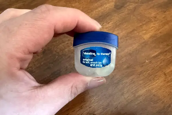 A person holding the Vaseline Lip Therapy Original Mini