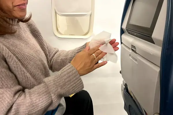 A person using a Wet Ones Antibacterial Hand Wipe on a plane