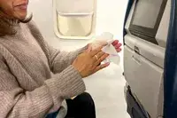 A person using a Wet Ones Antibacterial Hand Wipe on a plane