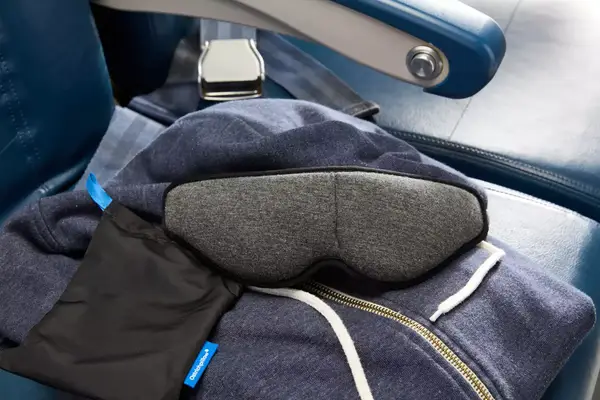The Ostrichpillow Ergonomic Eye Mask laid on an airplane seat