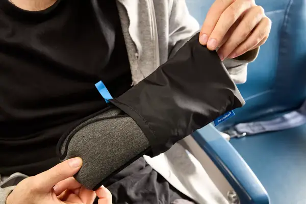 A person removing the Ostrichpillow Ergonomic Eye Mask from a travel pouch