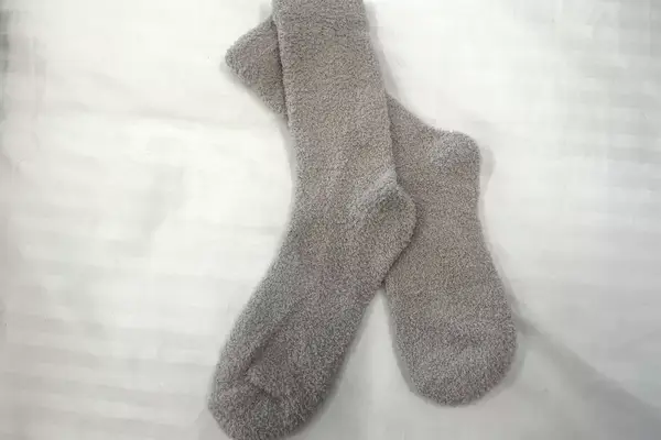 A pair of Shadow Breeze Plush Cozy Knit Socks on bedding
