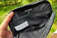Hand holds open lululemon Everywhere Belt Bag to show inside mesh pockets
