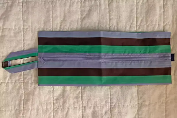 A travel pouch from the Baggu 3D Zip Set lying horizontally on a white blanket