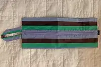 A travel pouch from the Baggu 3D Zip Set lying horizontally on a white blanket