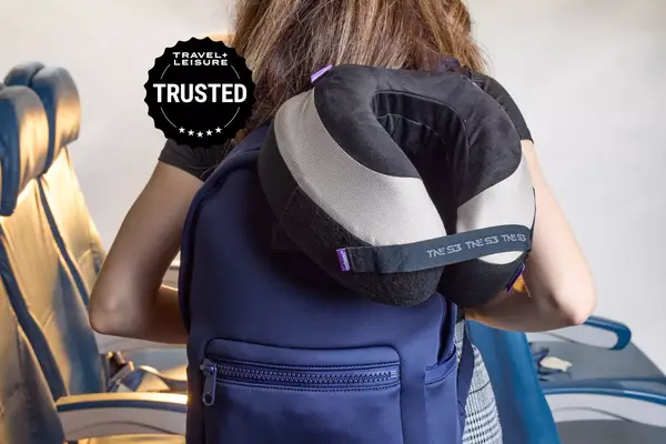 A person carrying a backpack with a travel pillow attached