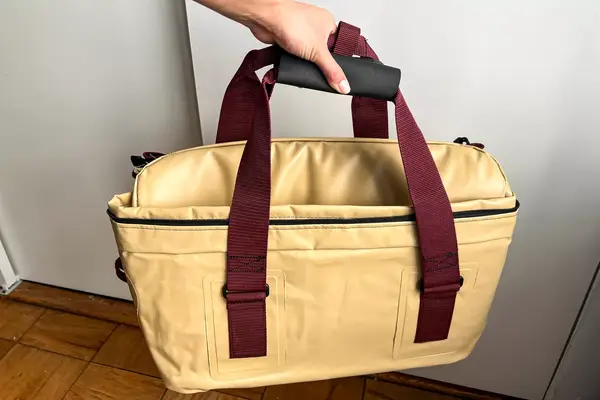 A person carries the Snow Peak Soft Cooler 38 by the top handles